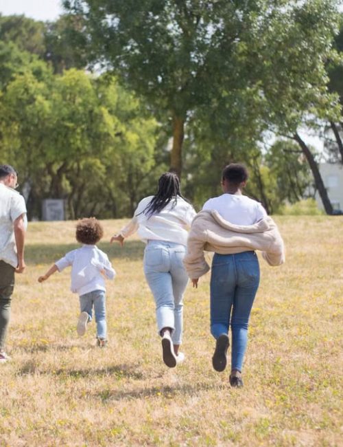 Cheerful family walking together in a sunny park surrounded by trees.